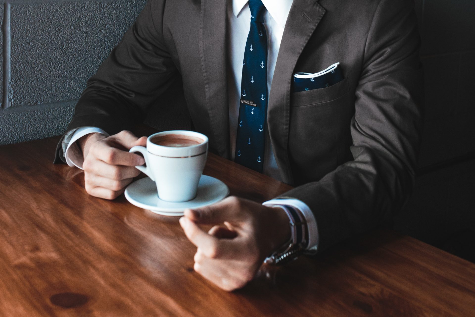 Man in suit holding a cup of coffee on a desk