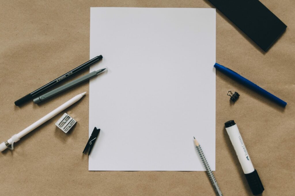 Blank piece of paper with pens and pencils around it