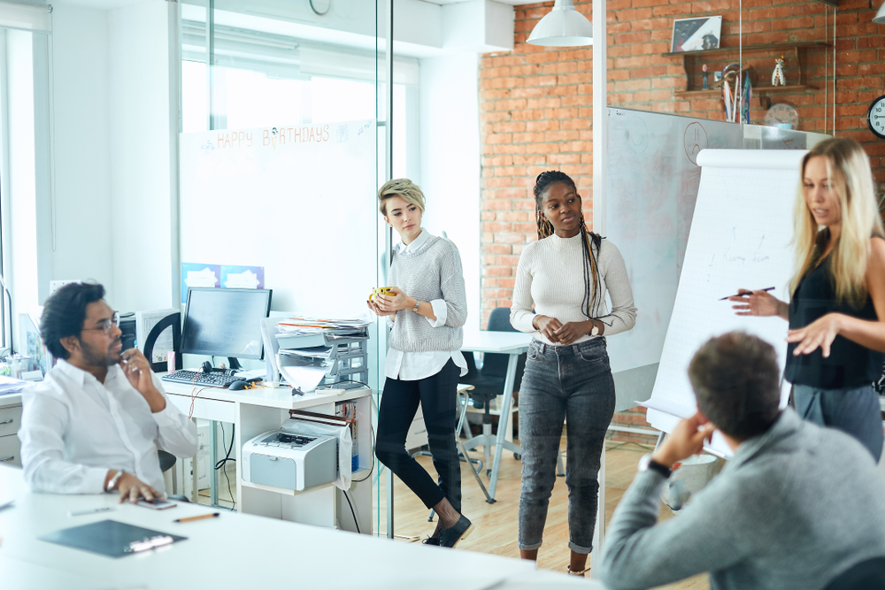 Mixed race interns listening to female manager