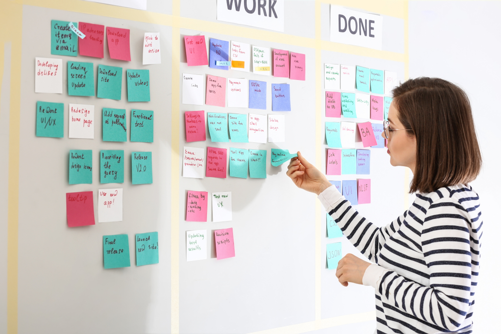 A woman sticking notes on a Kanban board