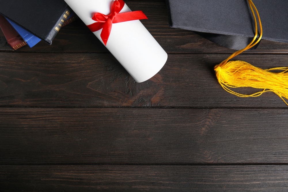 graduation cap and scroll on a wooden platform