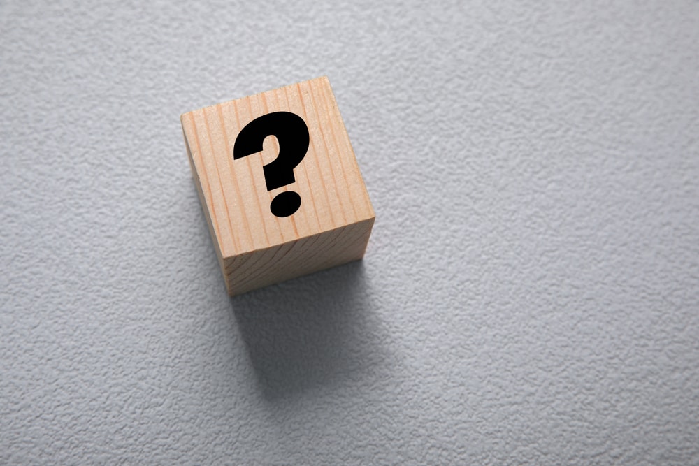 Question mark on wooden cube against grey background