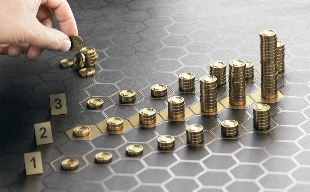 human hand stacking golden coins on black background with hexagonal golden shapes