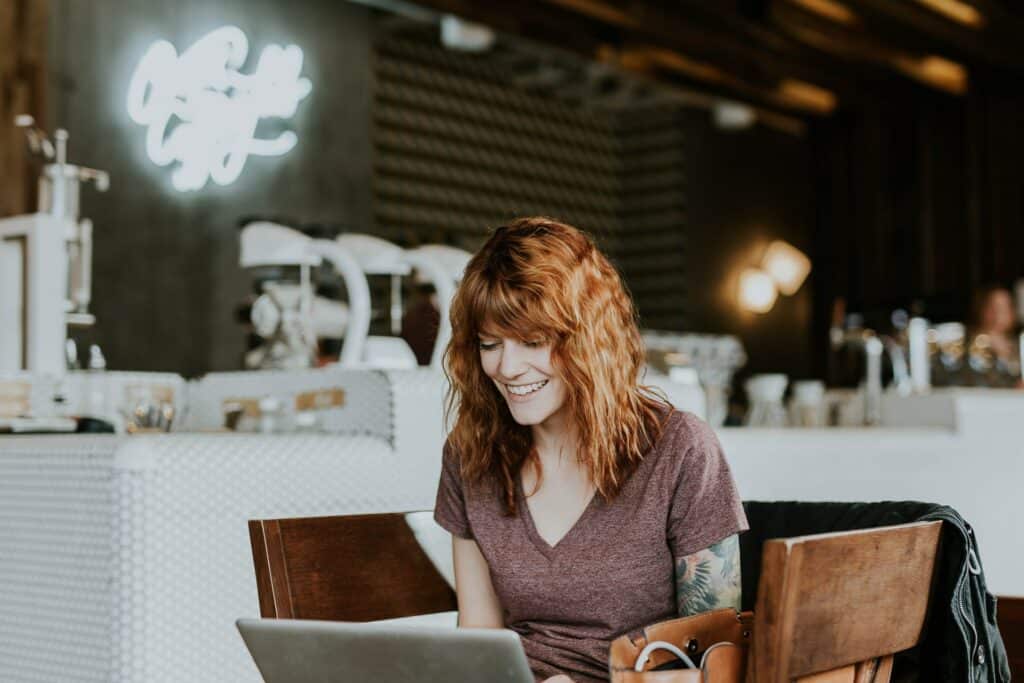 redhead woman smiling while working on her laptop