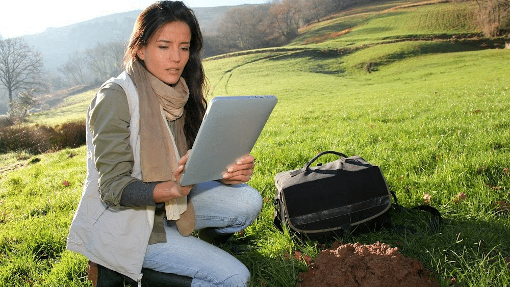 A female environmental intern working in the field, holding a tab