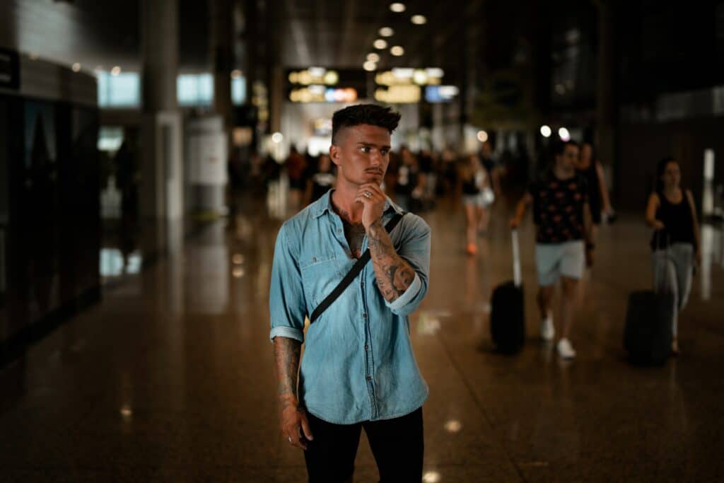 young man wearing a blue denim shirt holding his chin