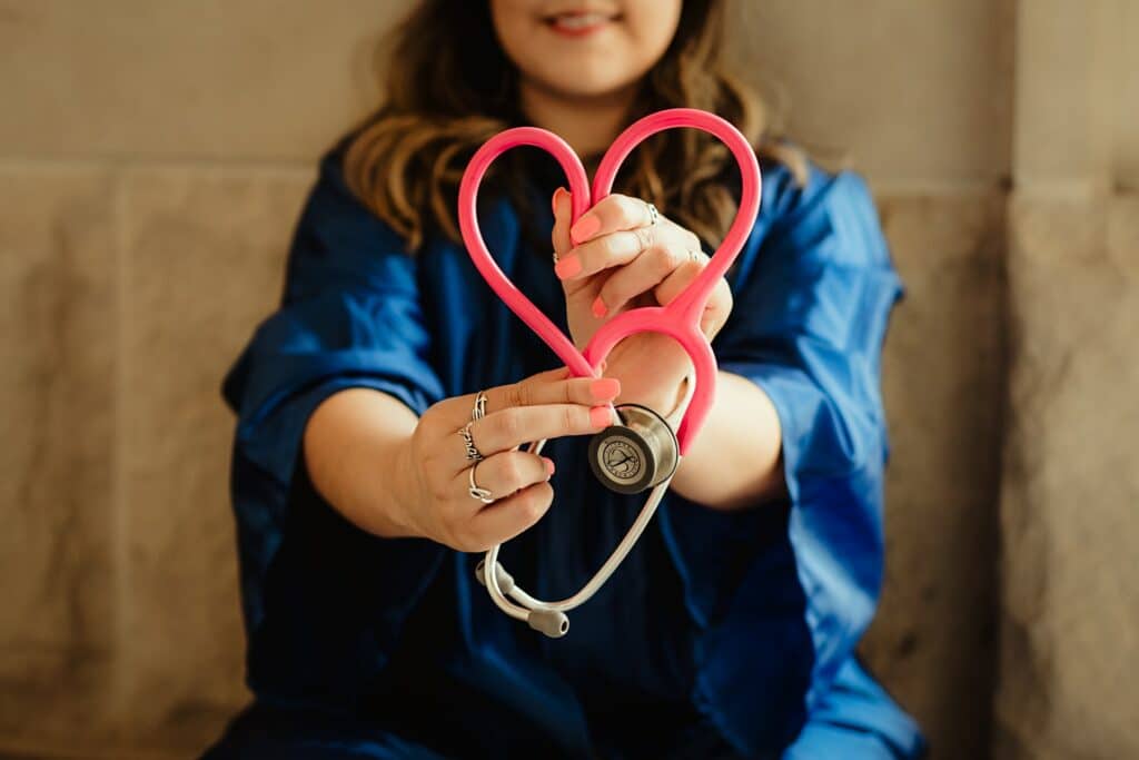 A female medical intern holding up a pink stethoscope