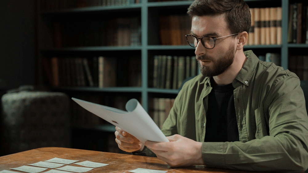 Male actor wearing glasses studying a script