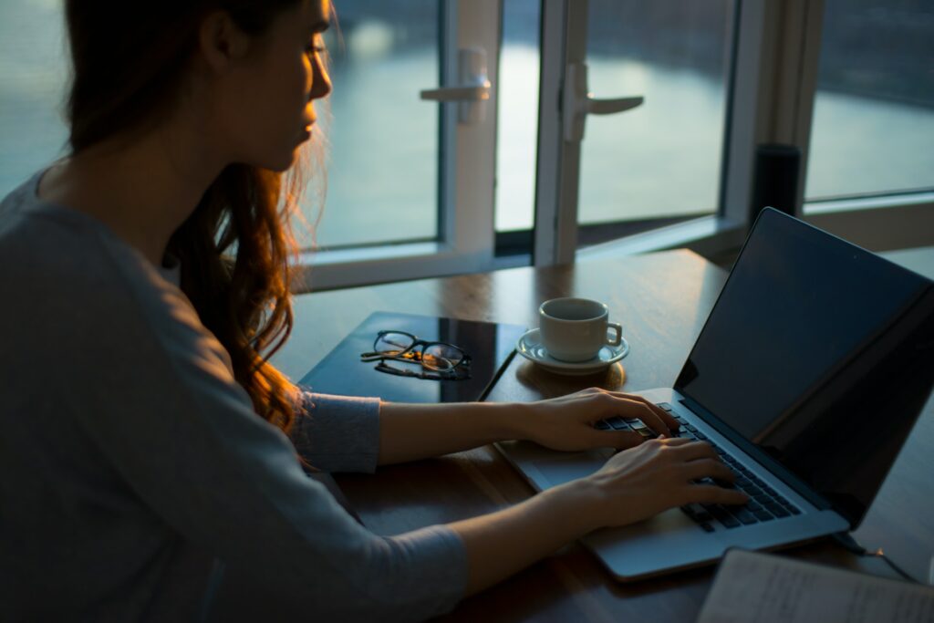 Woman typing on wooden table using a laptop