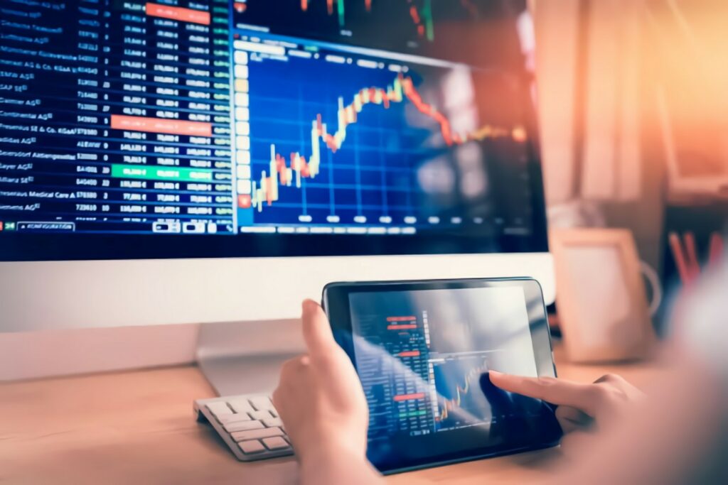 accountant using a computer and a tab while checking the stock market